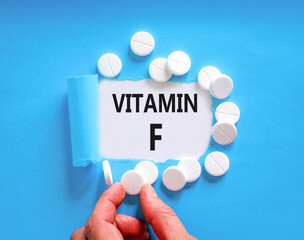 Vitamin F symbol. Concept words Vitamin F on beautiful white paper. White pills tablets. Doctor's...