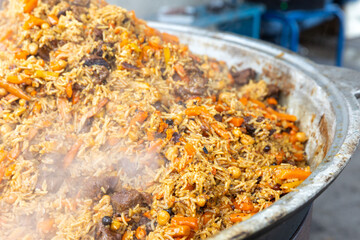 Steaming pilaf with meat, carrots, and chickpeas — street food warmth meets cultural tradition and smart cooking