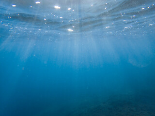 Light filtering down through blue water. Underwater sunlight in deep sea. Light viewed from blue abyss. Underwater sunlight shining deep with ripples on wave surface ocean ray, Mediterranean sea.