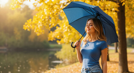 Woman in blue striped t-shirt holding navy umbrella in golden autumn park with warm sunlight. Casual fall fashion for everyday wear brands, umbrella accessory campaigns
