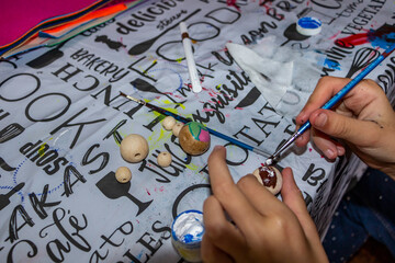 child holds a bead in his hands, for a necklace, paints wooden beads, paints, for bracelets, made...