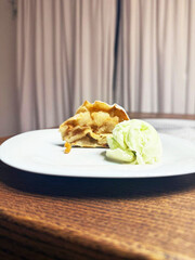 Apple pie slice with pistachio ice cream on white plate