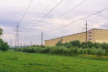 Industrial landscape with high-voltage power lines and green grass