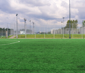Sports grounds and soccer field with green grass and blue cloudy sky in the background © Evgeny