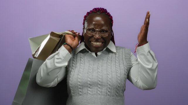 Woman smiling holding shopping bags over isolated purple background with joyful expression and surprise.