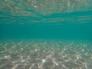 Fototapeta premium Light filtering down through blue water. Underwater sunlight in deep sea. Light viewed from blue abyss. Underwater sunlight shining deep with ripples on wave surface ocean ray, Mediterranean sea.