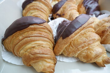 Golden flaky croissant pastries generously topped with rich dark chocolate promise truly delightful and indulgent sweet treat. perfect bakery item