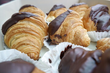Golden brown flaky croissants dipped rich dark chocolate evoke immense joy. Each sweet pastry offers delightful, decadent treat. perfect dessert