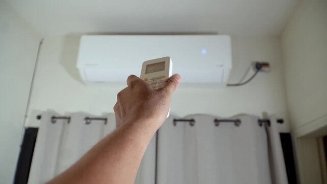 Person operating an air conditioner remote control