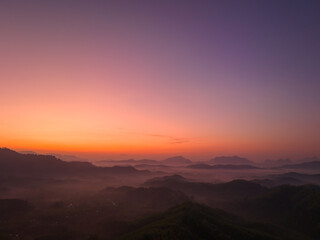 aerial view amazing colors in the sky at dawn over the misty sea in the valley. colorful sky at twilight above the mountain range. Mist covers the complicated mountain ranges.