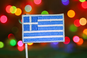 Greek flag embroidery with colorful bokeh lights resembling fireworks, symbolizing holiday...