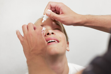 Doctor administering eye drops to a child in an ophthalmology clinic for pupil dilation or eye treatment. Pediatric eye care procedure