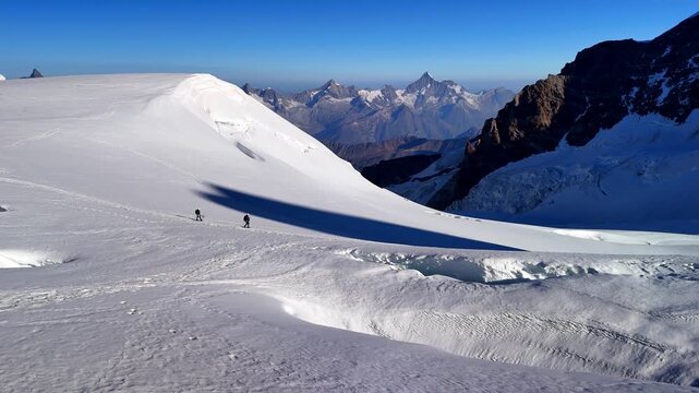 People trekking to Capanna Margherita, the highest mountain hut in Europe, located on Monte Rosa in the Italian Alps. Surrounded by glaciers, snowy peaks and alpine landscape. Italy