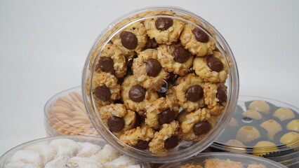 Homemade chocolate thumbprint cookies with peanut sprinkles arranged in a clear plastic jar, isolated on a clean white background. Perfect for dessert packaging mockups or food blogs