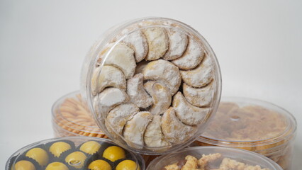 Homemade Putri Salju cookies coated in powdered sugar, stored in a transparent jar. Shot on a clean white background, perfect for festive food promotions and design assets