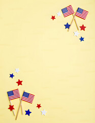 Obraz premium American flags and star decorations arranged on a bright yellow surface, celebrating patriotism.