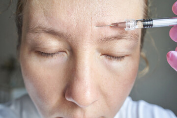 Female adult receiving botox injection in forehead for anti aging treatment close up view.