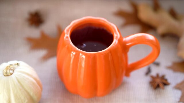 Orange pumpkin cup with hot black tea on the table. Autumn mood
