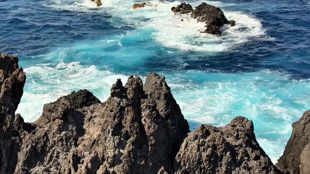 The stunningly beautiful waves are crashing vigorously against the jagged, rough rocks in a vibrant ocean setting