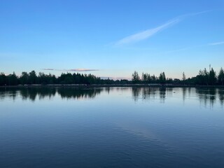 Tranquil lake with forest reflection in blue and green colors at dusk for nature relaxation or landscape photography 
