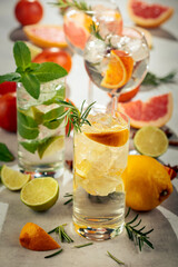 Refreshing summer cocktails with citrus on a white marble table.