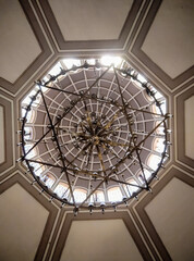 Symmetrical chandelier and dome ceiling with geometric architectural design, interior perspective. The photo was taken at the Neve Shalom Synagogue in Karaköy, Istanbul, Turkey.