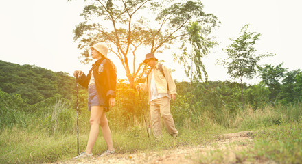 Active senior couple hiking on a trail through a lush green forest, enjoying outdoor nature, fitness, and adventure together.