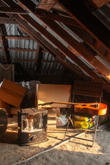 A sunlit attic with a guitar, heater, and aged wooden beams.