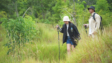 Fototapeta premium Active senior couple hiking on a trail through a lush green forest, enjoying outdoor nature, fitness, and adventure together.