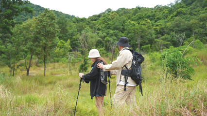 Fototapeta premium Active senior couple hiking on a trail through a lush green forest, enjoying outdoor nature, fitness, and adventure together.