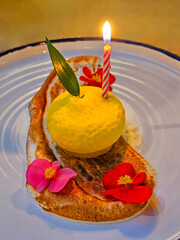 Birthday cake with a candle on a white platerated with flowers