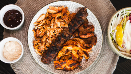 A beautifully arranged platter of grilled chicken shish, lamb shish, and doner kebab, served with...