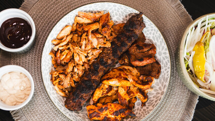 A beautifully arranged platter of grilled chicken shish, lamb shish, and doner kebab, served with...