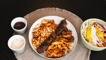 A beautifully arranged platter of grilled chicken shish, lamb shish, and doner kebab, served with vibrant sauces on the side. Elegant plating for food photography, menus, and promoting healthy, protei