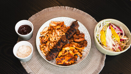 A beautifully arranged platter of grilled chicken shish, lamb shish, and doner kebab, served with vibrant sauces on the side. Elegant plating for food photography, menus, and promoting healthy, protei