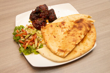 Spicy Beef Boti with Fresh Salad and Soft Naan Bread in plate side view of bangladeshi food
