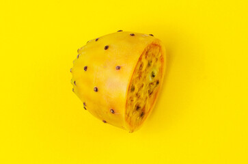 Side view of sliced cactus fruit with orange flesh and dark seeds on yellow background