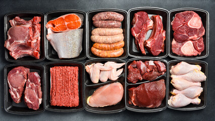 Raw fresh meat and fish in Black plastic packaging trays from supermarket. Top view. Food background.