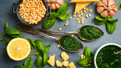 Pesto sauce. Metal spoon with traditional pesto sauce on a gray stone background. Close-up.