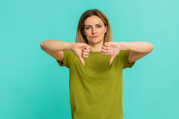 Middle-aged woman gives thumbs down with firm expression, showing disapproval, dissatisfaction,...