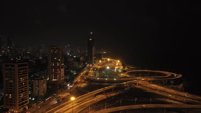 Cinematic aerial view of the Coastal road junction near Bandra Worli Sea Link in Mumbai city of Maharashtra, India, during the monsoon season at night.