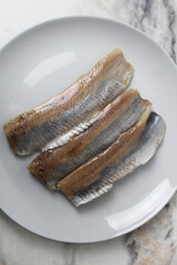 Pieces of herring fillet on a plate View from above. Preparation of fish dishes. horizontal photo