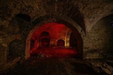 Dark and creepy vaulted red brick cellar under old castle