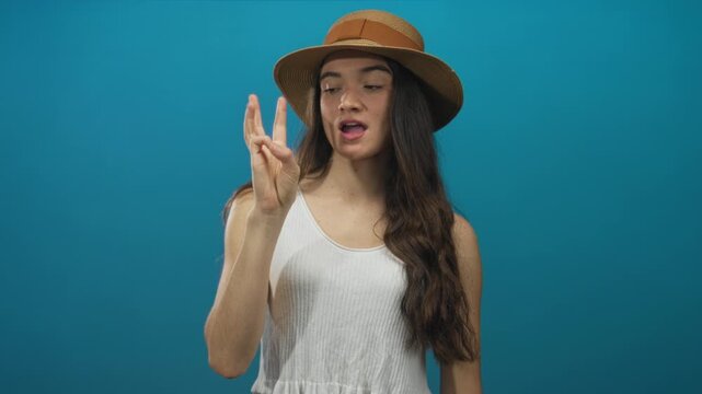 Teenage hispanic woman holds hand displaying sequential finger count in studio session; counting education joy.