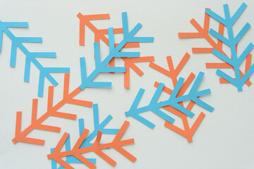 orange and blue twig or branch like paper cutouts scattered on blank paper