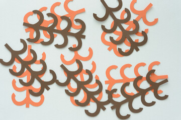 brown and orange machine-cut decorative paper shapes with linear and curve cutouts arranged on blank paper