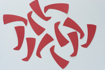 abstract red paper boot or comma shapes arranged randomly on blank paper