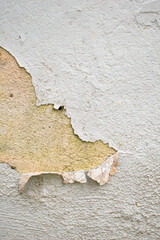 Imagen vertical de una pared desgastada con la pintura blanca cayendose