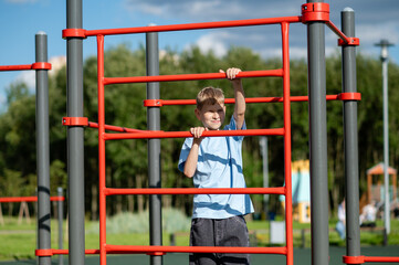 Teen boy climbing ladder on playground with sports equipment