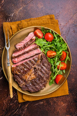 Dinner with Grilled Rib eye steak, fried dry aged beef meat. brown background. top view